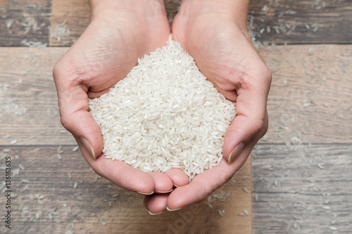 Rice in the hands on the wooden table in the kitchen. Healthy eating and lifestyle.