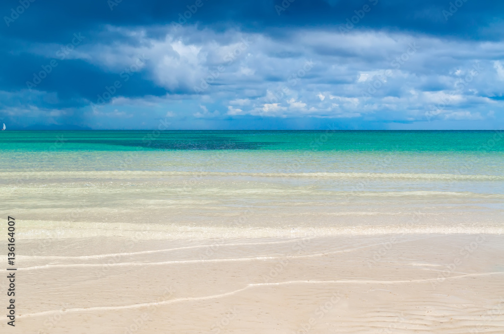 Obraz premium Rain clouds over the sea and white-sand beach with clear water