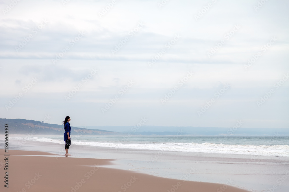 Lonely and depressed woman watching the sea in a deserted beach on an Autumn day. Lonely and depressed woman watching the sea in a deserted beach on an Autumn day.
