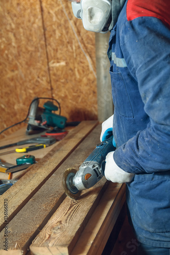 Wallpaper Mural Man carpenter mills the piece of wood by a grinding machine in his home workshop Torontodigital.ca