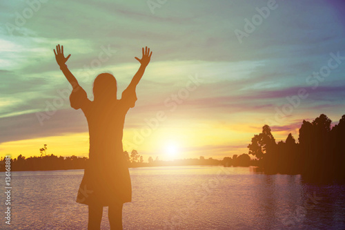 Silhouette of woman praying over beautiful sky background