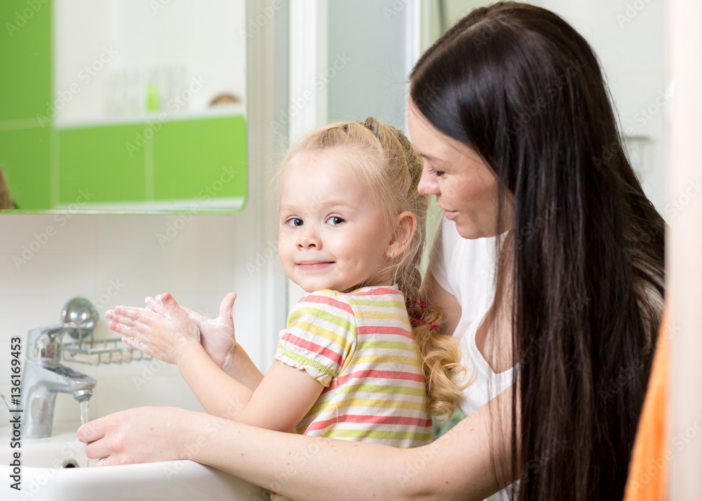 Woman and her daughter kid girl washing hands with soap in bathroom Woman and her daughter kid girl washing hands with soap in bathroom