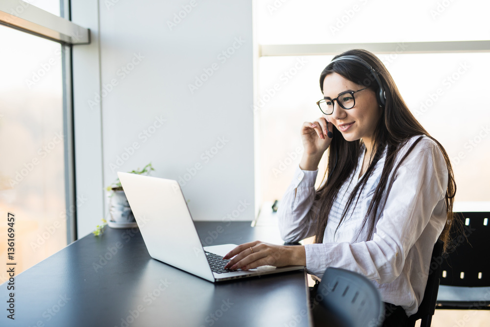 businesswoman talking on the phone while working on her computer at the office businesswoman talking on the phone while working on her computer at the office