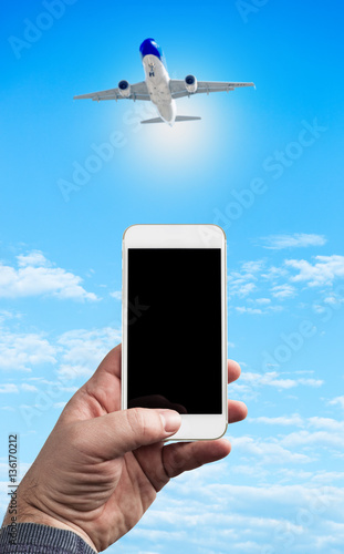 Man Hand holding using mobile phone and airplane on a blue backg