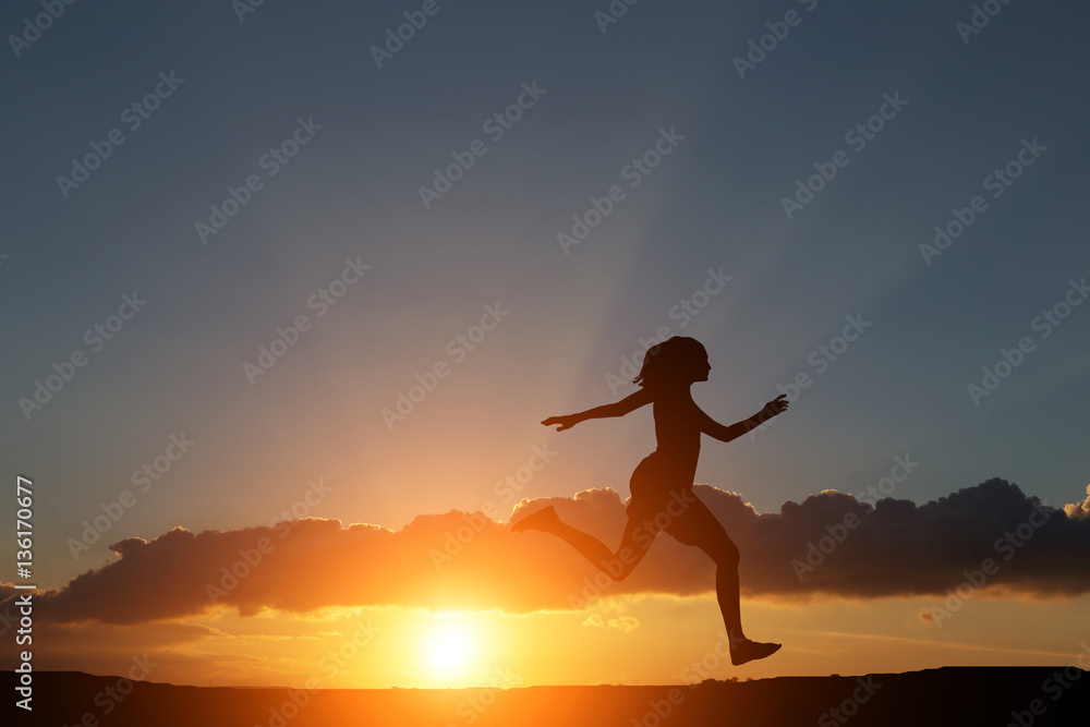 silhouette of a girl running on the hillock right in the beautiful sunset and sea