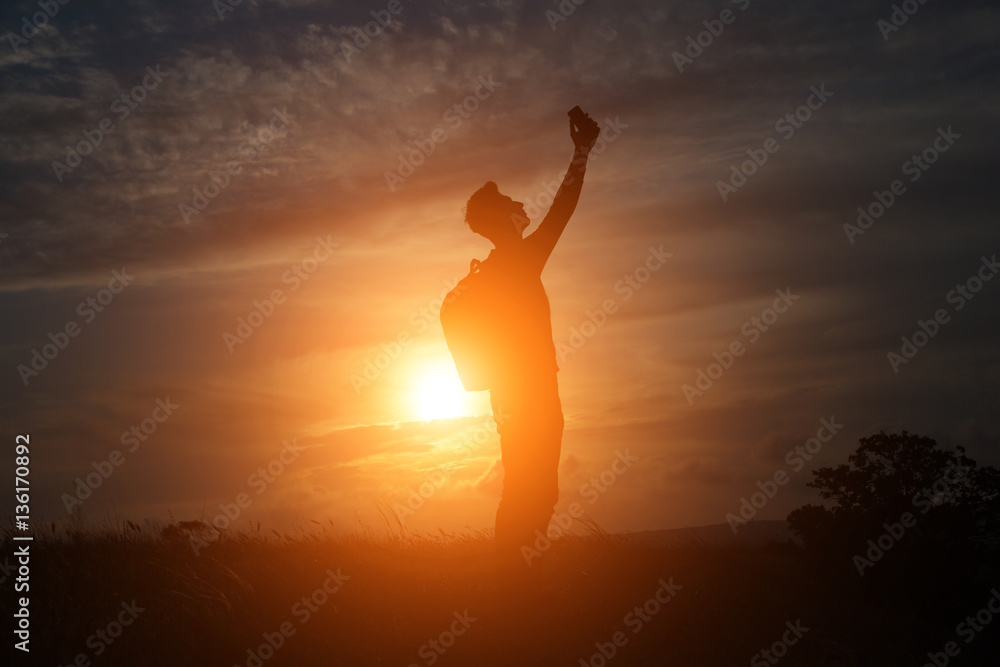 a man standing on a hill looking link on the background of a beautiful sunset