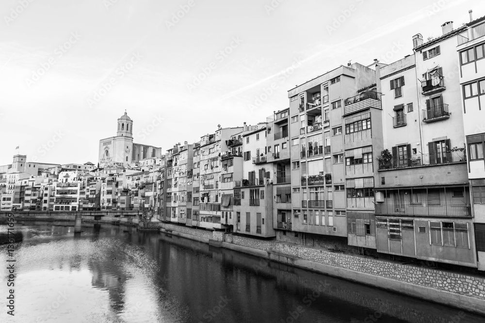 Onyar river crossing the downtown of Girona with bell tower of gothic Cathedral of Saint Mary in background. Gerona, Costa Brava, Catalonia, Spain. Monochrome image: black and white.