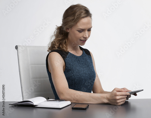 Business woman sitting in her office using a tablet computer