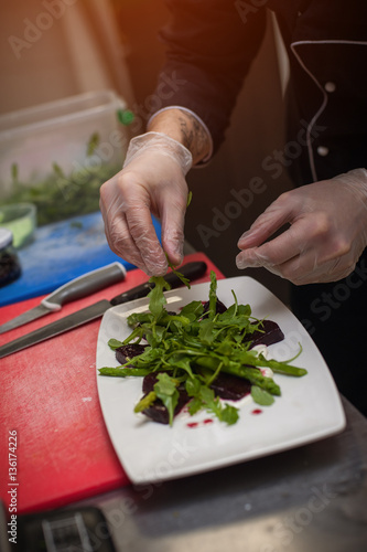 Male chef preparing salad with arugula and beet