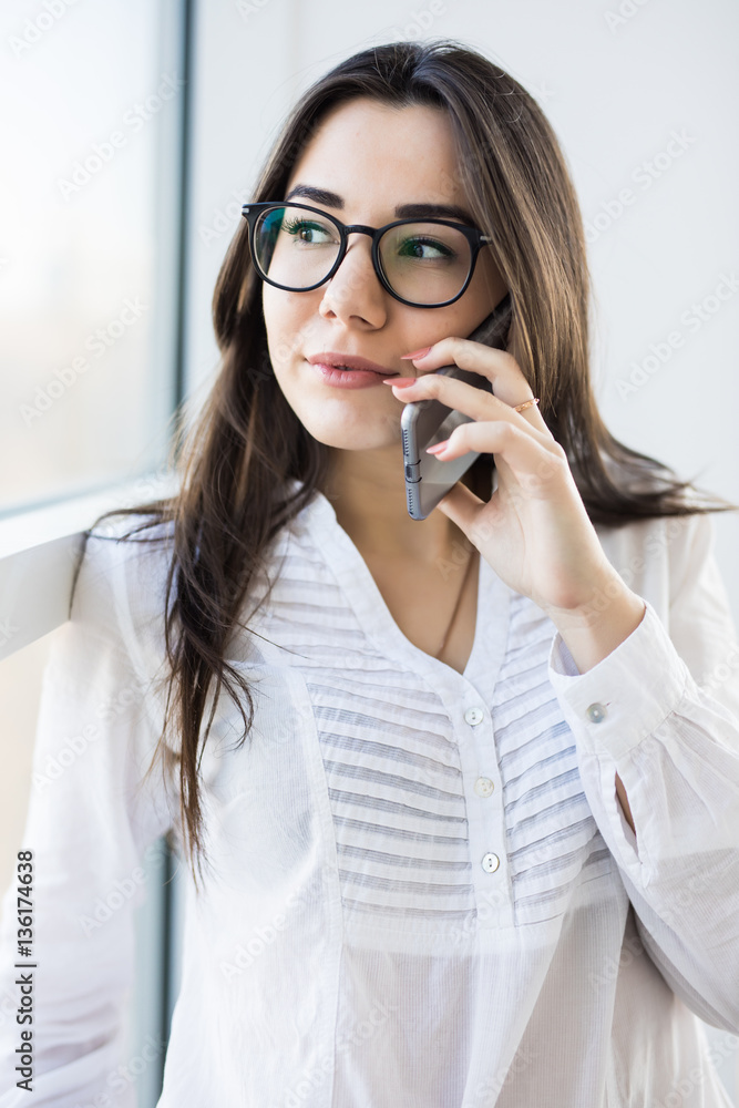 Business woman speak on phone near big office windows in modern smart space. Business woman speak on phone near big office windows in modern smart space.