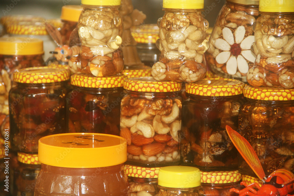Орехи и мед в баночках на прилавке, большой выбор