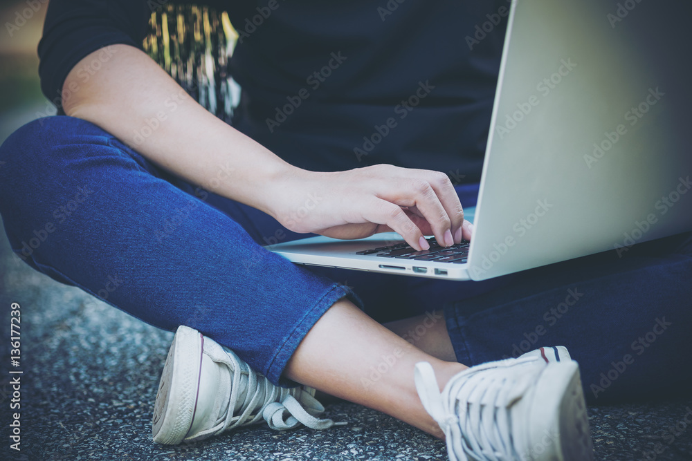 A woman sitting on the road and using laptop with nature background A woman sitting on the road and using laptop with nature background