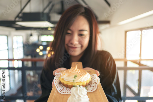 A Beautiful asian woman holding and showing with sweet dessertes with feeling happy and good lifestyle  in the cafe