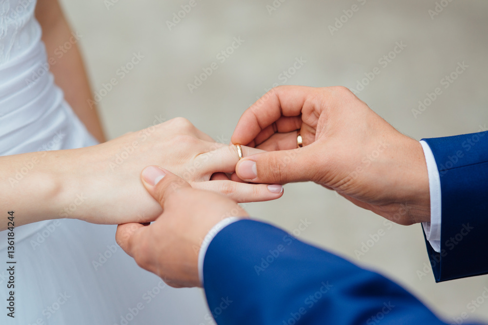 Closeup of groom placing ring on brides finger on their Closeup of groom placing ring on brides finger on their