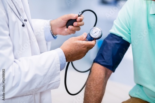 Mid section of doctor checking blood pressure of a patient