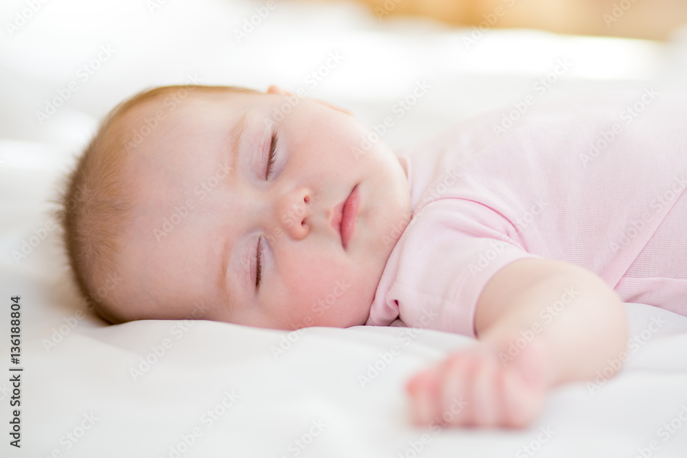 Sweet baby infant lying on a bed while sleeping in a bright room Sweet baby infant lying on a bed while sleeping in a bright room