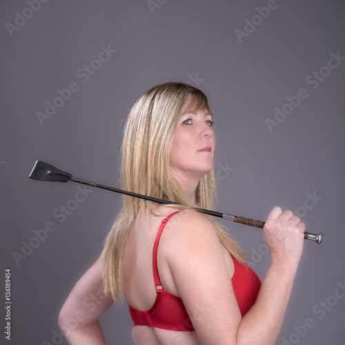 Blond woman holding a leather riding crop