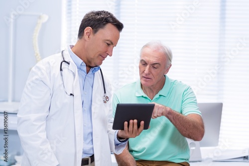 Doctor and senior patient using digital tablet