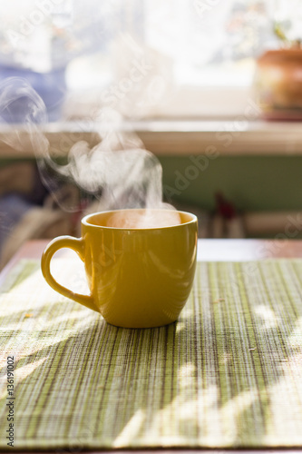 Steam of morning tea above yellow cup on table