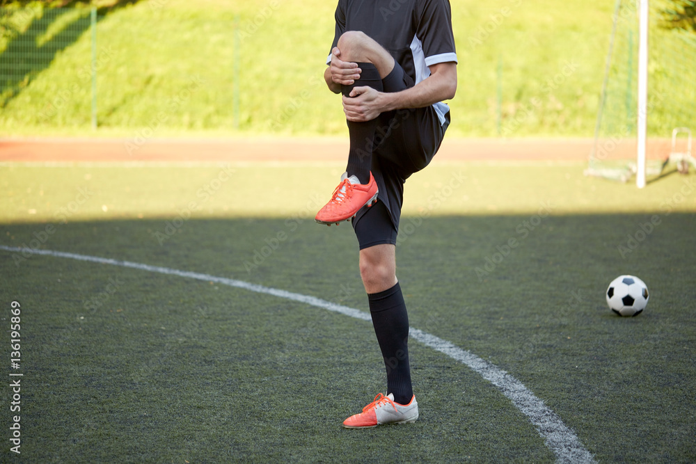 soccer player stretching leg on field football