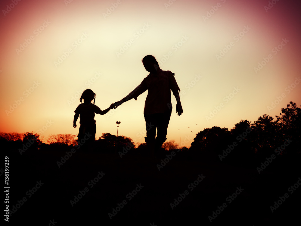 silhouette of mother and little daughter play at sunset