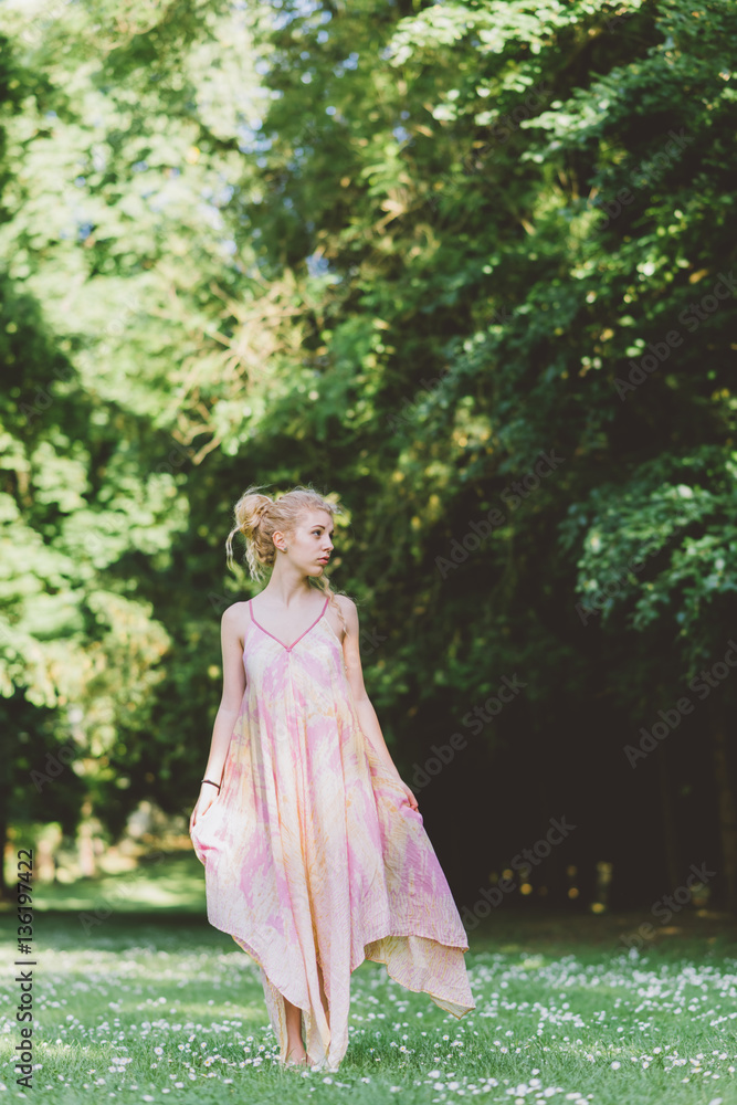 Young beautiful blonde hair woman wearing pink dress standing in the forest - adventure, magic, dreamy concept