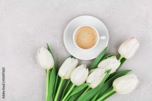 Coffee mug with spring tulip flowers for good morning on gray stone table top view in flat lay style. Breakfast on Mothers or Womens day.