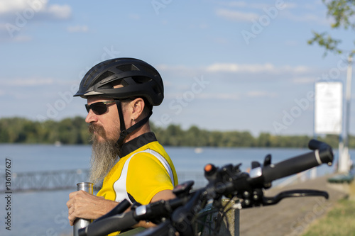 Cyclist taking a rest on a bench near river