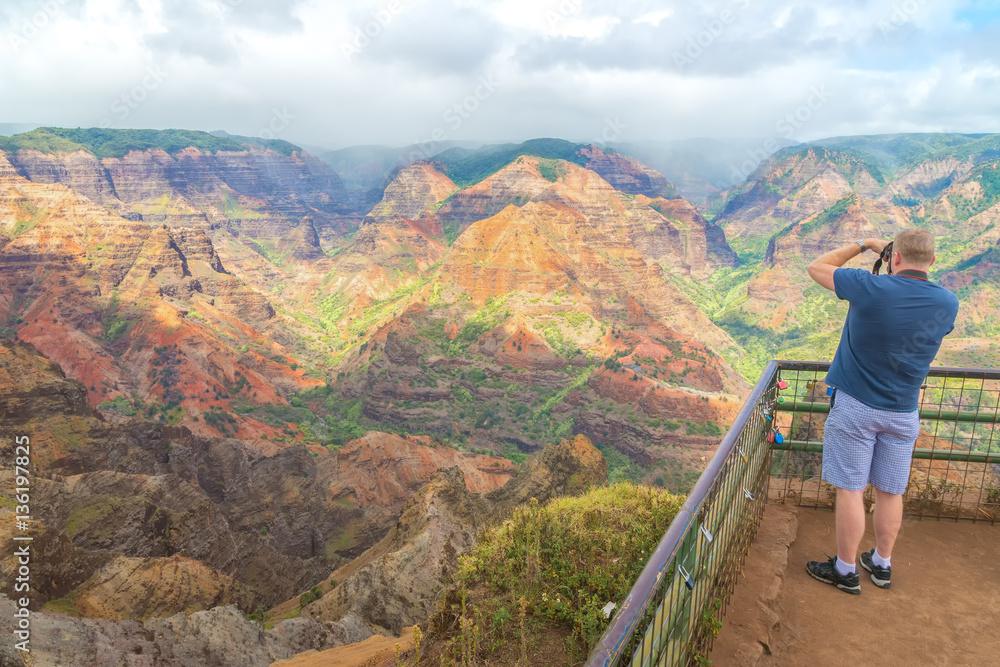 Tourist taking pictures of the beautiful views in Waimea Canyon, Kauai Island, Hawaii