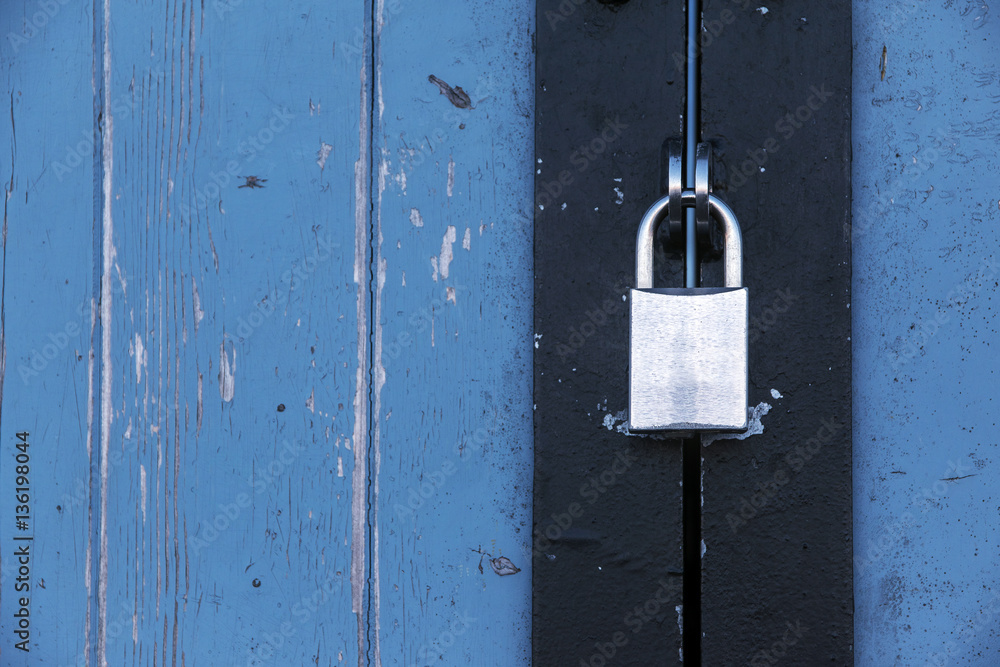 Silver padlock on an old blue wooden door, concept background Silver padlock on an old blue wooden door, concept background