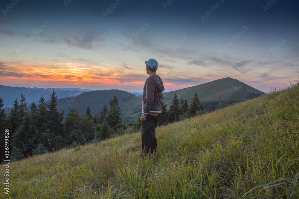boy watching the sunset in the mountains
