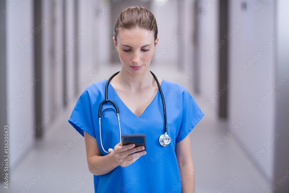 Female doctor using mobile phone in corridor Female doctor using mobile phone in corridor