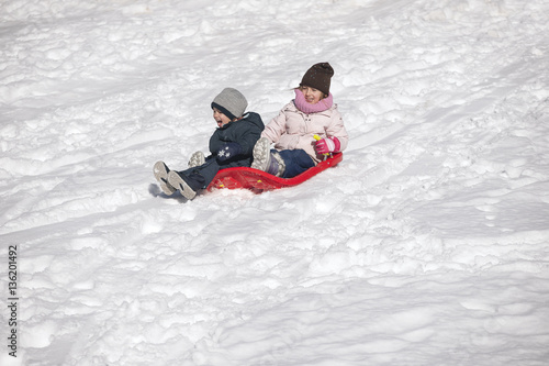 Brother and sister on toboggan on snow covered hill