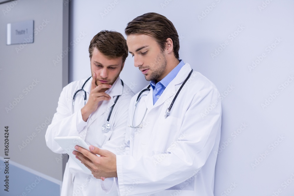 Doctors using digital tablet in corridor Doctors using digital tablet in corridor