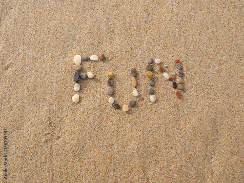 word fun written with stones and shells on the beach by the ocean