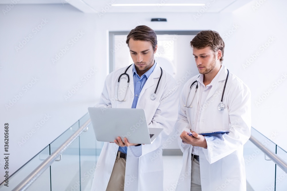 Doctors using laptop in corridor Doctors using laptop in corridor