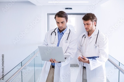 Doctors using laptop in corridor