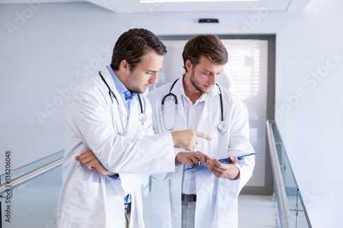 Doctors having discussion on clipboard in corridor