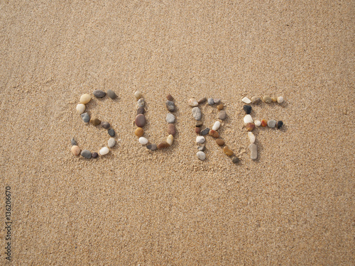 word surf written with stones and shells on the beach by the ocean