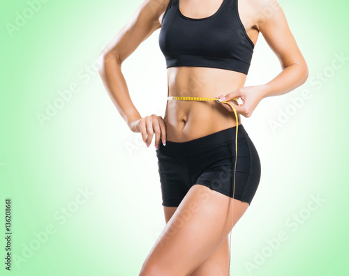Fit, healthy and sporty woman in sportswear measuring her body i