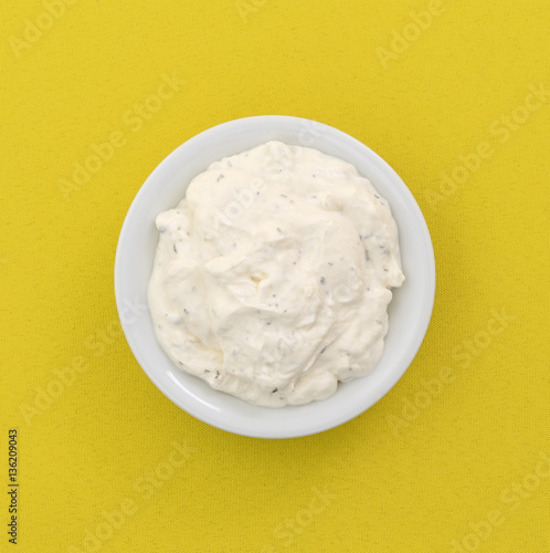 Top view of a small bowl of French onion dip on a yellow tablecloth.