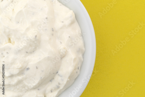 Top close view of a small bowl of French onion dip on yellow tablecloth.