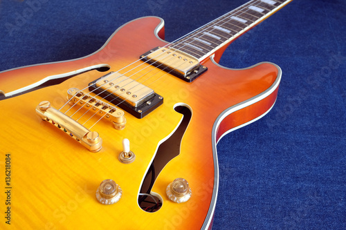 Part of vintage semi-hollow body electric guitars with pickups, electronics knobs and metal accessories on jeans background closeup