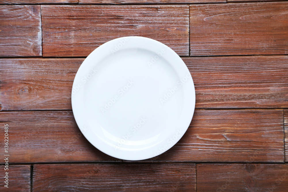 Empty plate on brown wooden table Empty plate on brown wooden table