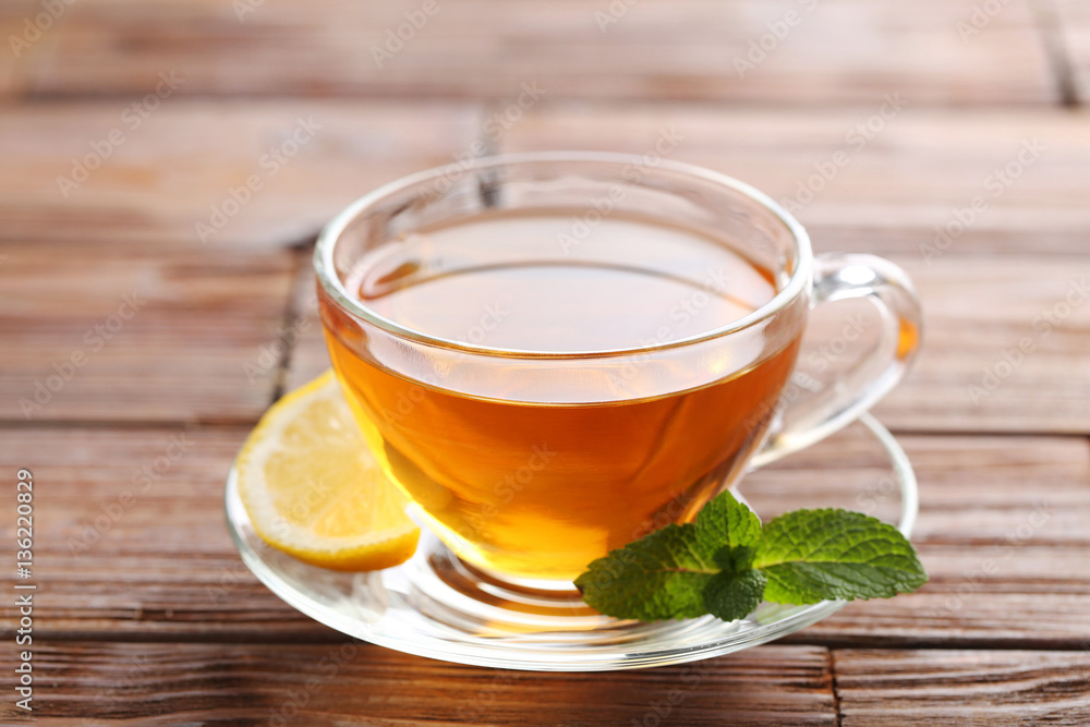 Cup of tea with mint and lemon on brown wooden table Cup of tea with mint and lemon on brown wooden table