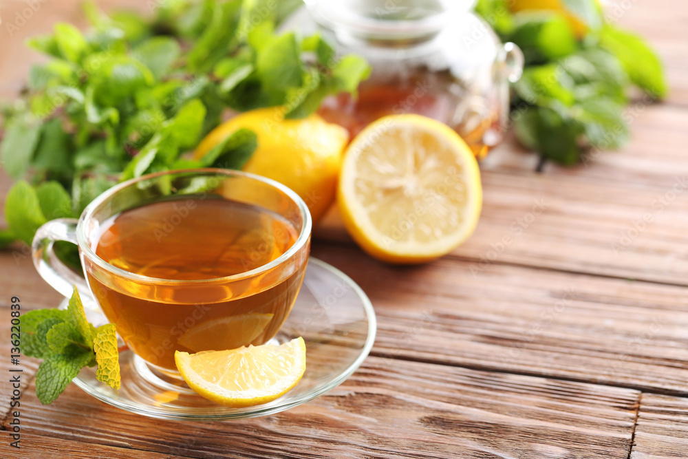 Cup of tea with mint and lemon on brown wooden table Cup of tea with mint and lemon on brown wooden table