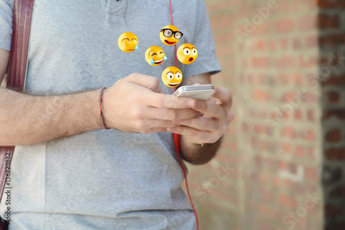 Man using smartphone sending emojis.