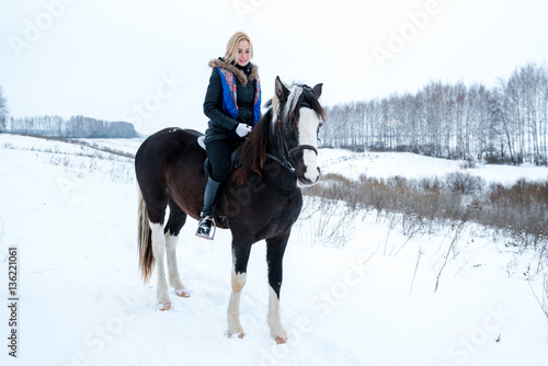 Attractive beautiful young woman wintering with a horse on natur