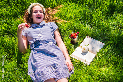 Girl reading a book on the green lawn in bright sunny day photo