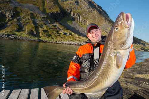 fisherman happy man holding a huge fish Cod. Pier. horizontal po